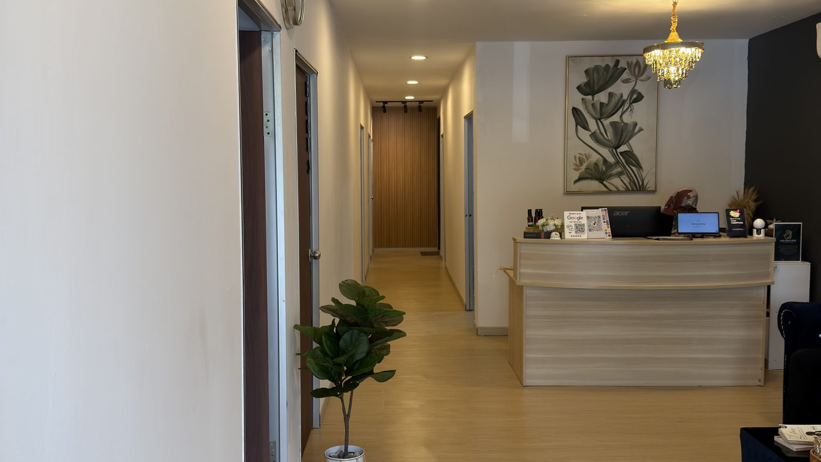 Renovated lobby — hallway symmetry, vinyl flooring, wood slat wall and chandelier (IMG_1063, centre crop 16:9)